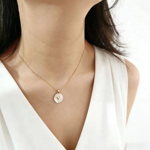Dettaglio della collana d'oro con ciondolo esagonale in conchiglia bianca e cuore