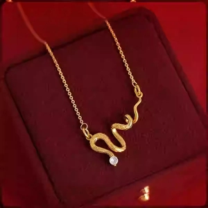Dettaglio collana con ciondolo a serpente dorato e zircone su sfondo in velluto rosso