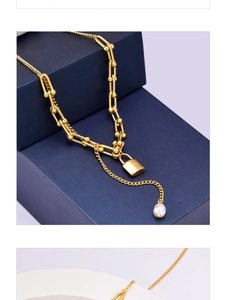 Close-up of golden U-link chain necklace with square lock charm and white pearl detail