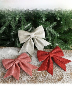 Detail of red, pink, and silver glitter Christmas bows on snowy pine branches