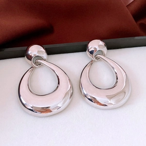 Macro detail of silver-tone teardrop earrings with a high-polished metallic mirror finish