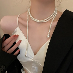 Sautoir en perles blanches style vintage français avec pendentifs baroques sur mannequin