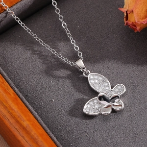 Detailed close-up of a silver bow necklace with pearls and crystals in a velvet jewelry box