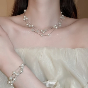 Detail of layered white pearl necklace and bracelet set with elegant silver chain finish