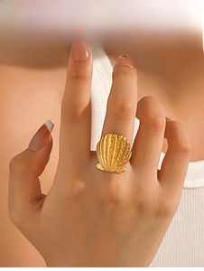 Detailed view of a large golden seashell ring with realistic textured patterns on a finger