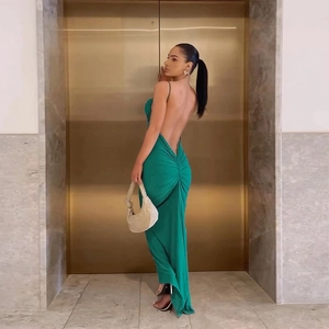 Detail of emerald green backless dress with ruched waist and thin straps in a luxury setting