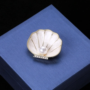 Macro shot of white enamel shell brooch with a central pearl and small diamonds