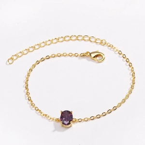 Detail of gold-plated chain bracelet featuring purple oval gemstone and lobster clasp