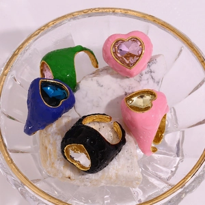 Detailed macro shot of 18K gold plated colorful heart gemstone rings in glass bowl
