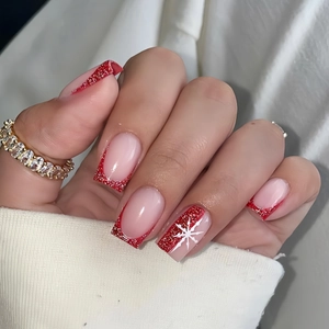 Detail of square french press-on nails with red glitter gradient and snowflake motif
