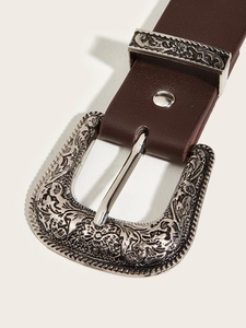 Detail of silver western floral engraved buckle on a dark brown leather studded belt