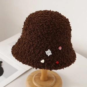 Détail du chapeau bob en peluche marron café avec badge chat mignon et décor de cœur