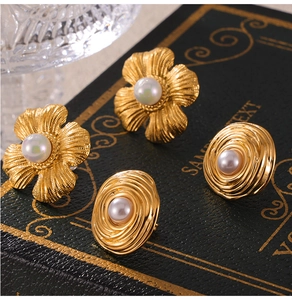 Macro detail of retro gold-plated floral and textured disc earrings with pearl inlays