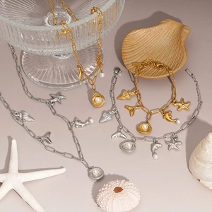 Marine charm jewelry set with starfish, seashell and pearl on a purple beach background