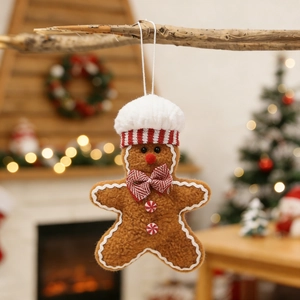 Close-up of gingerbread man plush ornament hanging on branch with festive bokeh background