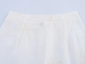 Detaillierte Nahaufnahme der weißen Baumwoll-Leinen-Hose mit feiner beiger Blumenstickerei