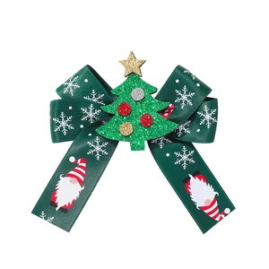 Close-up of a Christmas hair clip with a green snowflake ribbon and glittery tree