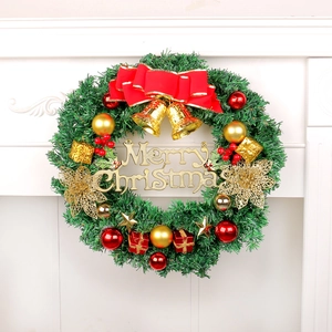 Detail of Christmas wreath with red bow, gold bells and Merry Christmas sign on white mantel