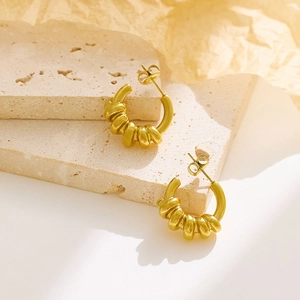 Detail showing the croissant texture of gold C-shaped twisted hoop earrings on stone
