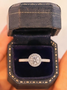 Vue macro d'une bague halo en diamant avec anneau pavé dans un écrin en velours bleu