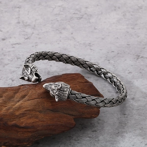 Close-up of vintage wolf head steel bracelet on driftwood showing woven metal texture