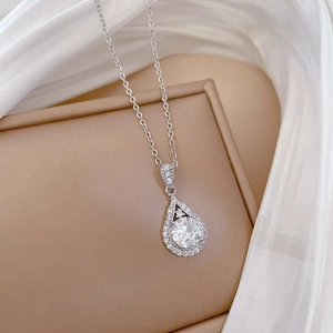 Close-up of a silver pear-shaped pendant with halo micro-pave setting on silk