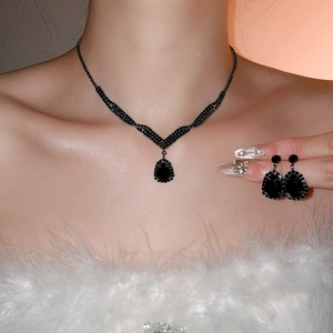 Detail of luxury water drop black crystal pendant necklace and earrings set worn by a model