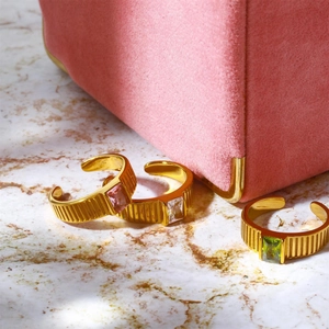 Detailed close-up of golden birthstone rings with pink, clear and green gemstones