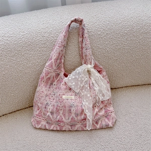 Detail of pink lace tote bag featuring intricate floral embroidery and a white polka dot bow