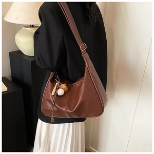 Detail of retro brown leather hobo bag with unique baseball charm and adjustable strap