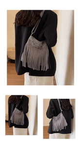 Macro shot of grey suede crossbody bag featuring long bohemian tassels and woven texture