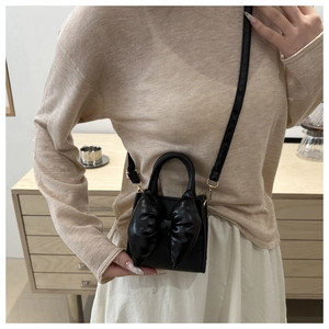 Close-up of the stylish black mini crossbody bag with a large decorative bow on the front