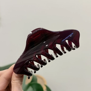Macro detail of large dark red translucent resin hair claw clip with smooth polished finish