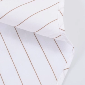 Close-up of white poplin fabric with fine brown stripes showing stitching details