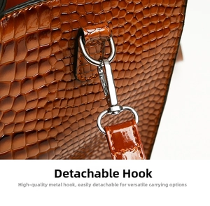 Detail of silver detachable metal hook and glossy brown crocodile pattern leather strap
