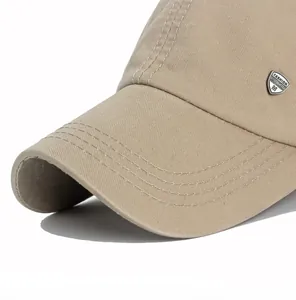 Detail of khaki cotton baseball cap showing reinforced brim stitching and metal shield logo