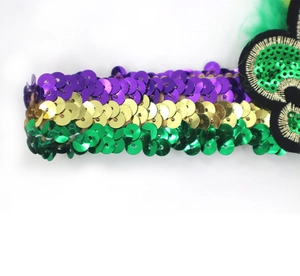 Detailed close-up of Mardi Gras sequins in purple, gold, and green on a party headband