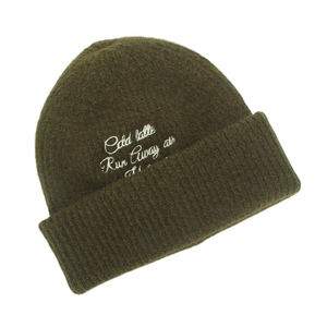 Close-up of olive green knit beanie featuring white cursive letter embroidery detail