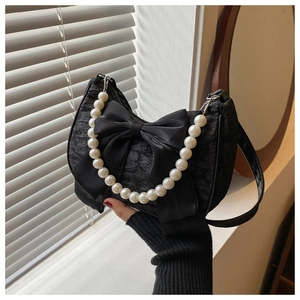Detail of black pleated bag featuring a large satin bow and premium faux pearl handle