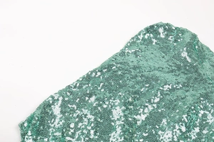 Detailed macro view of vibrant green sequins on a sexy off-shoulder cocktail dress fabric