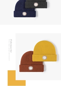 Detail of four ribbed knit beanies in navy, grey, yellow, and brown with smiley patch