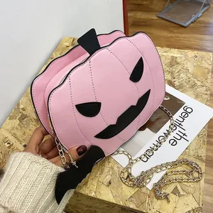 Close-up of pink pumpkin shaped crossbody bag with black bat detail and golden chain strap