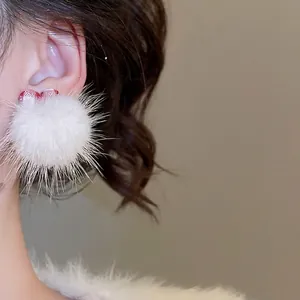 Winter style white faux fur ball earrings with red plaid bow tie shown on model