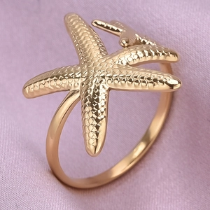 Macro detail of 18K gold plated starfish ring with realistic textured surface on silk