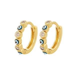Detalle de pendientes de aro dorados con ojo turco, esmalte azul y piedras de circón