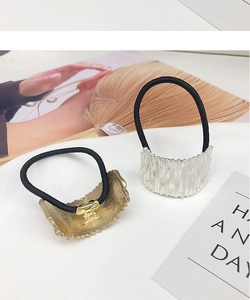 Detail view of wavy texture metal hair ties in gold and silver on a minimalist background