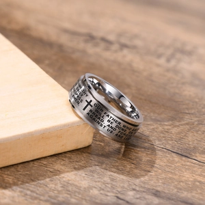 Close-up of rotatable stainless steel cross ring featuring engraved Lord's Prayer text