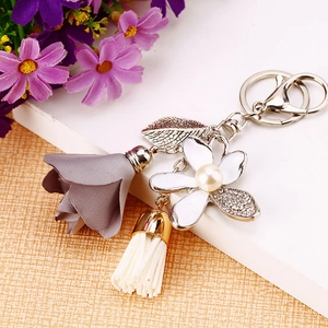 Floral keychain with white enamel flower, grey fabric ornament and pearl tassel on metal ring