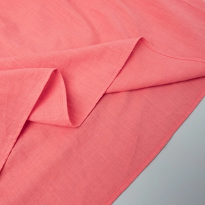 Detailed macro view of coral pink cotton fabric with precision double stitching and woven texture