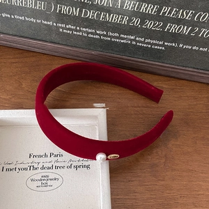 Detail of red velvet headband featuring a white pearl and gold metal charm accent